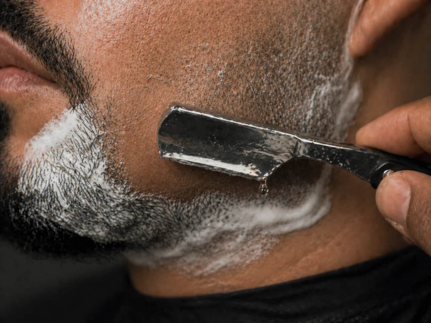 Barbeiro fazendo a barba na navalha, com modelagem masculina, em Joinville